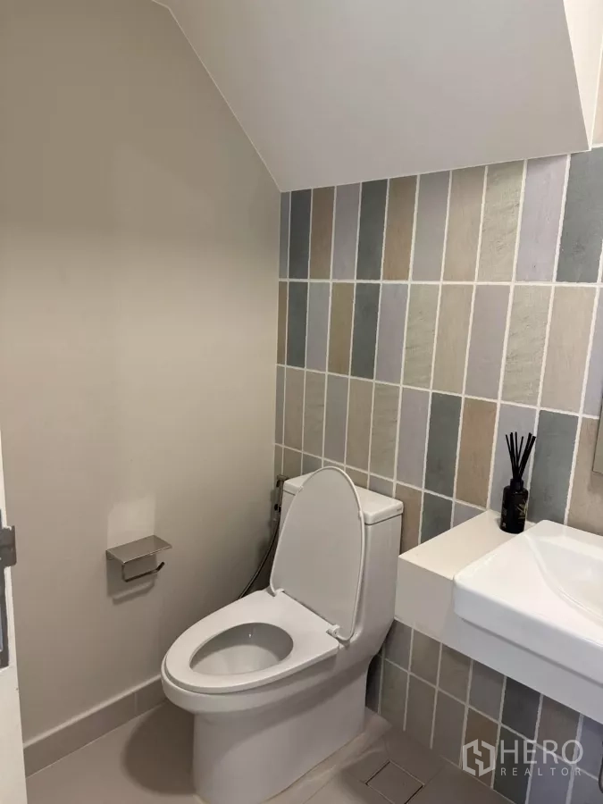Townhouse for rent in Bang Phli, Samut Prakan - Compact guest toilet with patterned wall tiles and white sanitary ware.