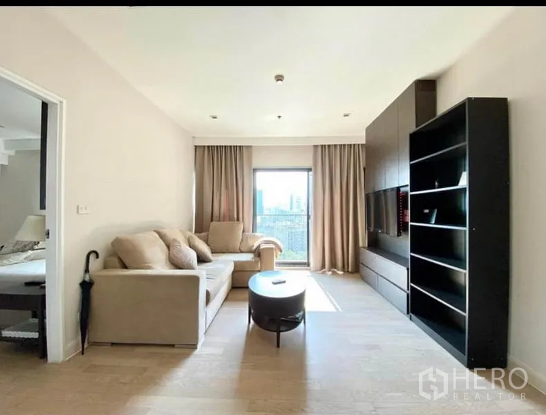 Condominium for rent in Khlong Toei, Bangkok - Cozy living room with two sofas, a coffee table, TV wall unit, and doorway to the bedroom.