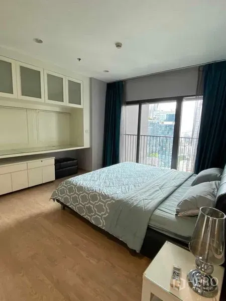 Condominium for rent in Khlong Toei, Bangkok - Bright master bedroom with city-view windows, balcony access, built-in cabinetry and wood floors.