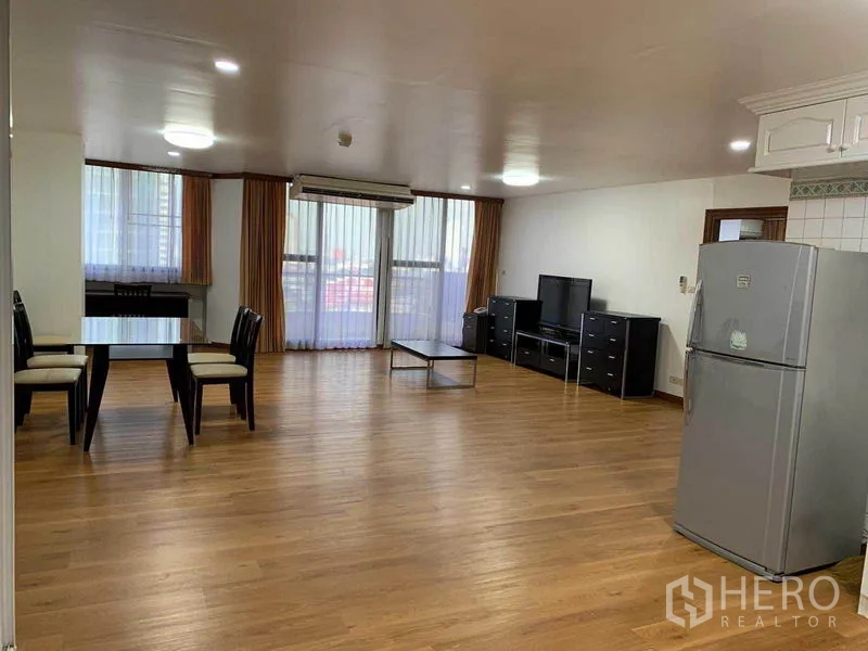 Condominium for rent or sale in Watthana, Bangkok - Spacious open-plan living and dining area with wood floors, large windows, air conditioning, and TV console.