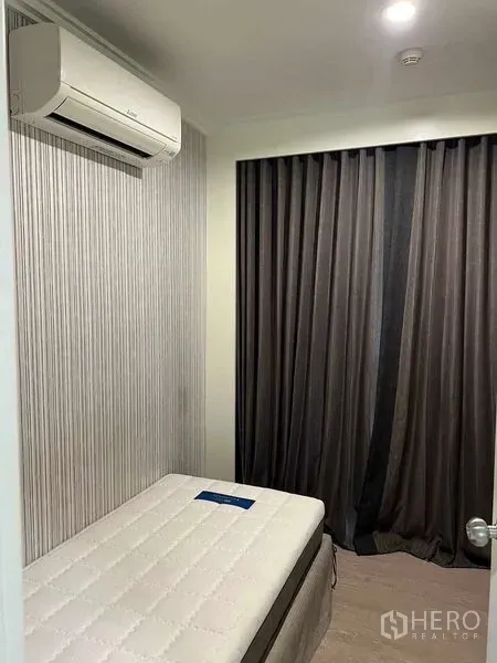 公寓 出售在Bang Na, Bangkok - 温馨卧室，单人床、空调与遮光窗帘。