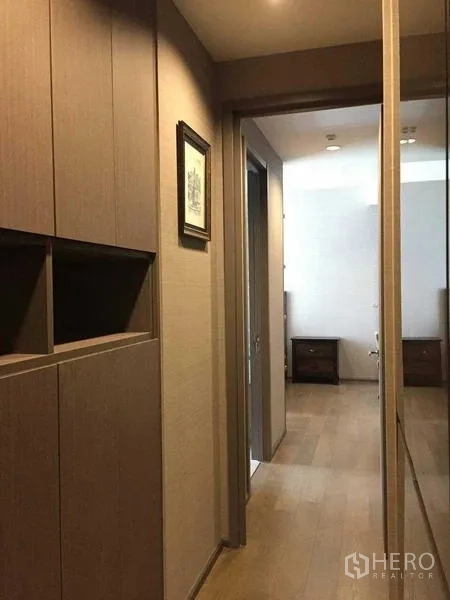 Condominium for rent in Bang Rak, Bangkok - Hallway with built-in wardrobes and mirrored panel leading to the bedroom in a Sathorn–Silom condominium.