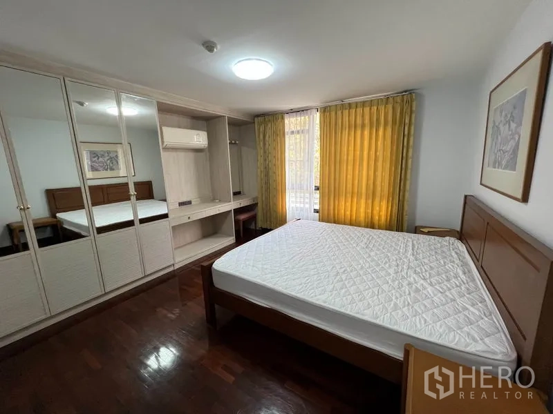 คอนโด ให้เช่าในWatthana, Bangkok - ห้องนอนพร้อมตู้เสื้อผ้าบิวท์อินกระจก เตียงไม้ ผ้าม่านสีเหลือง และโต๊ะทำงาน