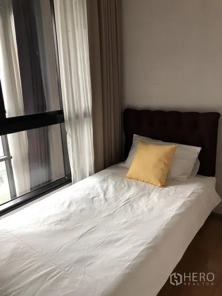 公寓 出租或出售在Khlong San, Bangkok - 次卧配单人床、黄色抱枕与转角落地窗帘。