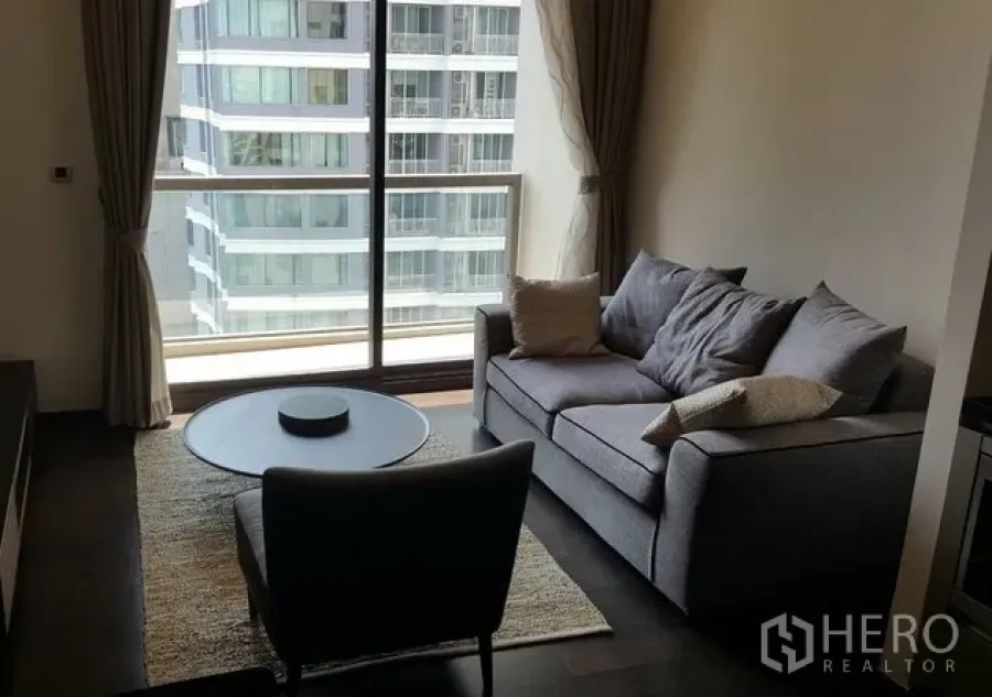 公寓 出租或出售在Watthana, Bangkok - 明亮客厅，落地窗、灰色沙发与城市景观的现代公寓。