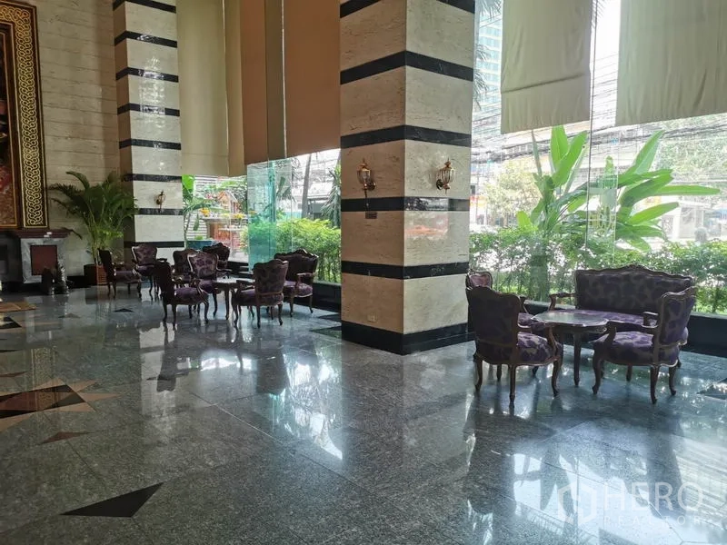 公寓 出租在Watthana, Bangkok - 豪华大堂，石材地面、条纹立柱与落地窗旁的古典座椅。