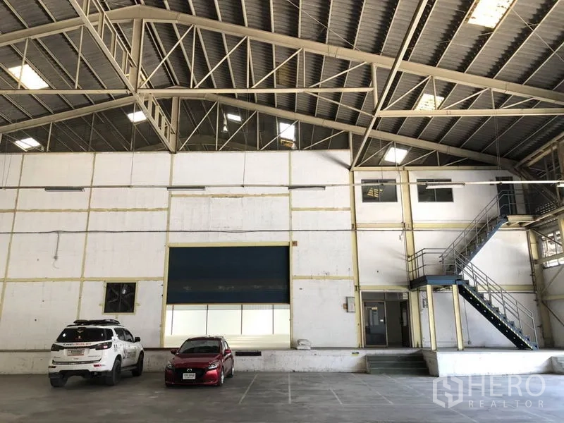 货栈 出租在Mueang Samut Prakan, Samut Prakan - 仓库正墙，展示大型卷帘门与楼梯，屋顶为钢结构桁架。