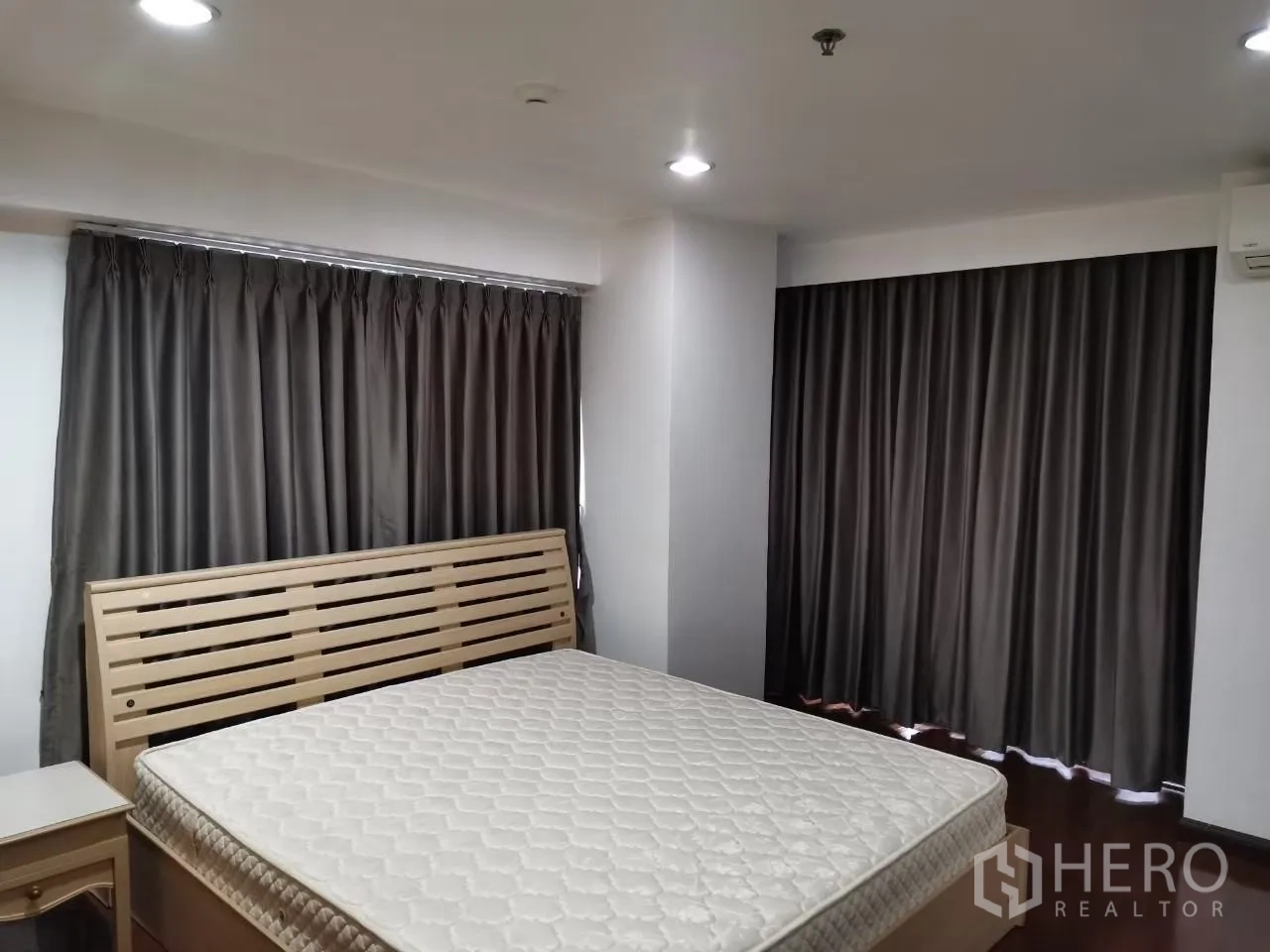 Condominium for rent in Phaya Thai, Bangkok - Bedroom with wooden bed frame and mattress, recessed lights and dark blackout curtains.