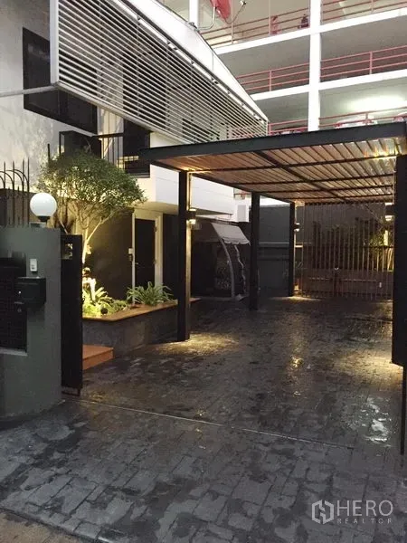 Detached House for rent in Watthana, Bangkok - Modern house entrance with covered carport, landscaped planter and warm exterior lighting in Ekkamai, Bangkok.