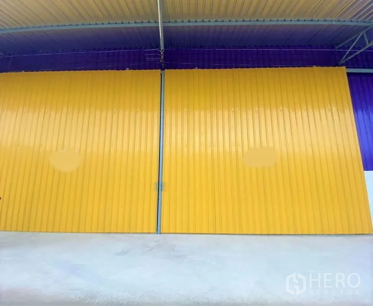 Warehouse for rent in Mueang Nonthaburi, Nonthaburi - Close view of large sliding metal doors beneath a sheltered loading bay.