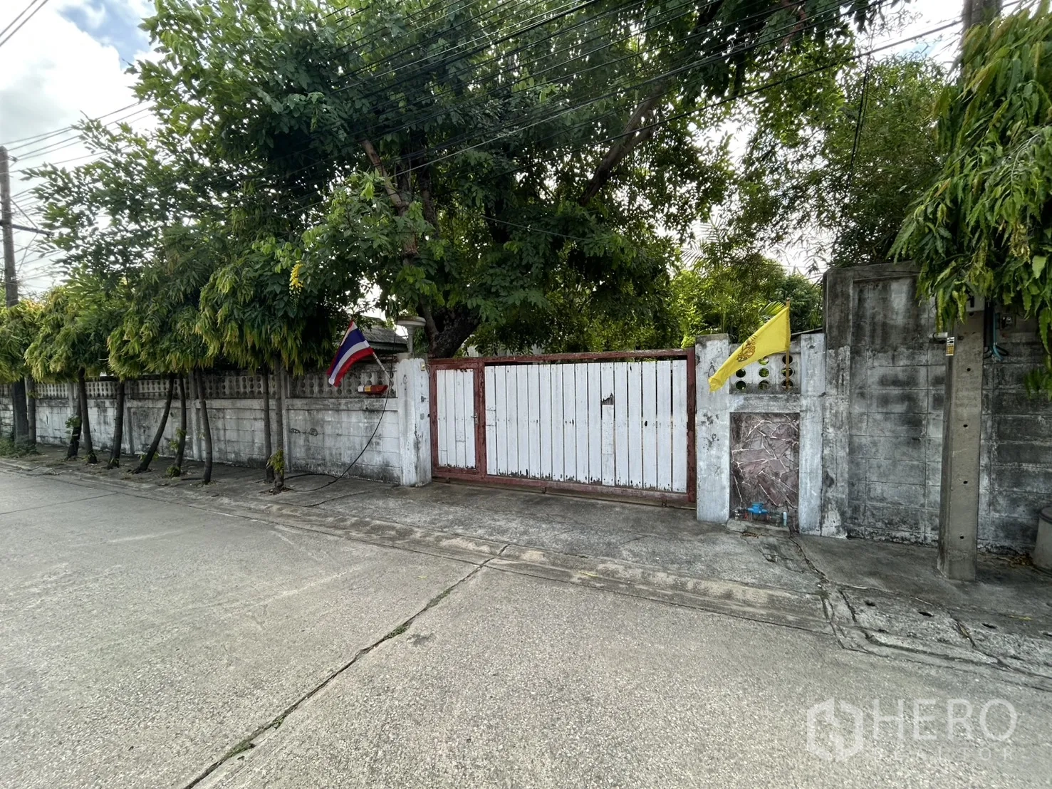 Detached House for sale in Phra Khanong, Bangkok - Street view of the walled property with a sliding wooden entrance gate.