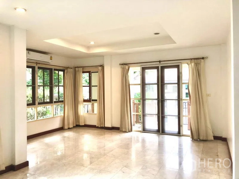 Detached House for rent in Saphan Sung, Bangkok - Living area with French doors to the terrace and wide corner windows for natural light.
