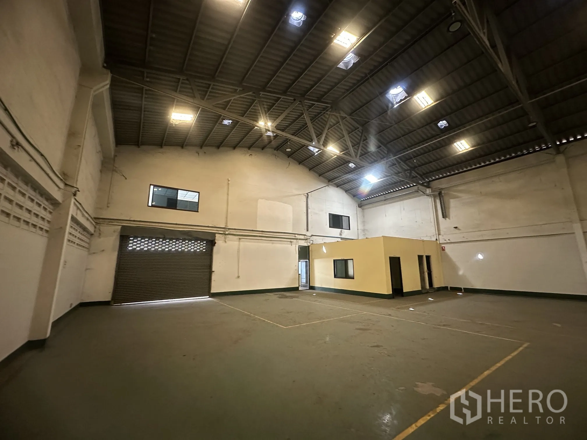 Factory for rent in Lat Lum Kaeo, Pathum Thani - Warehouse interior showing roller shutter access, high ceiling, and an office block.