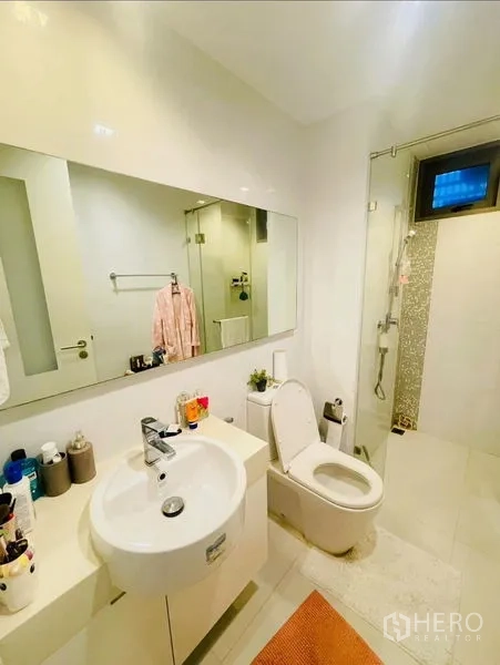 Condominium for rent or sale in Sathon, Bangkok - Bright guest bathroom with vanity, large mirror and walk-in shower.