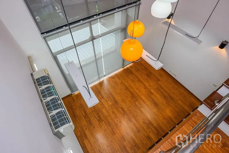 Townhouse for rent in Watthana, Bangkok - View from mezzanine over the double-volume living space with hanging lamps and wood floor.