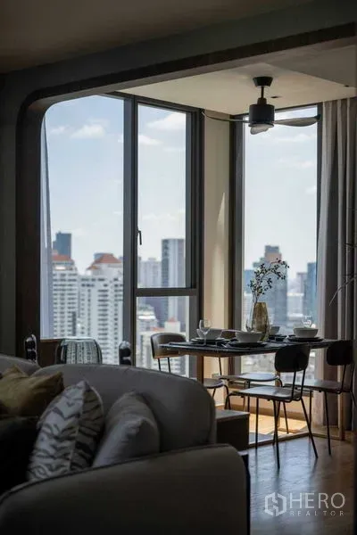 Condominium for sale in Khlong Toei, Bangkok - Corner dining nook by floor-to-ceiling windows overlooking the Thonglor skyline.