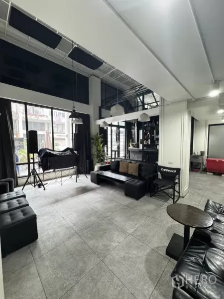 店屋 出租在Khlong Toei, Bangkok - 宽敞接待休闲区，落地窗、黑色沙发并连接紧凑吧台。