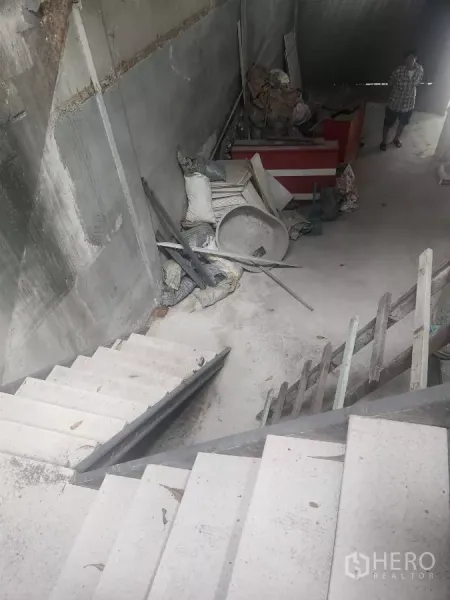 Shophouse for rent in Watthana, Bangkok - Concrete stairwell and unfinished interior space with scattered construction materials.