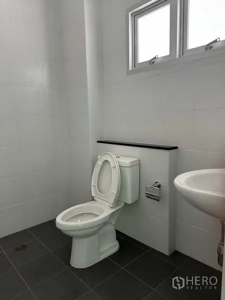 Factory for rent in Bang Sao Thong, Samut Prakan - Clean restroom with toilet, sink, tiled walls, and ventilation window.