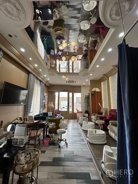 Retail Space for rent in Khlong Toei, Bangkok - Wide view of the salon showing reflective ceiling with chandeliers, workstations, and glass doors to a balcony.
