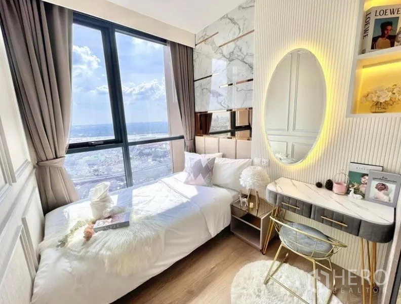 Condominium for rent in Khlong Toei, Bangkok - Sunlit bedroom with floor-to-ceiling window, marble accent wall, built-in vanity and expansive city view.