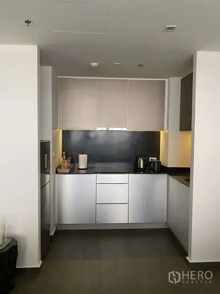 公寓 出售在Watthana, Bangkok - 现代紧凑厨房，简洁柜体，黑色背板与橱柜下灯光。
