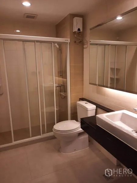 Condominium for rent in Watthana, Bangkok - Contemporary bathroom with glass-enclosed shower, large mirror, square basin and toilet.