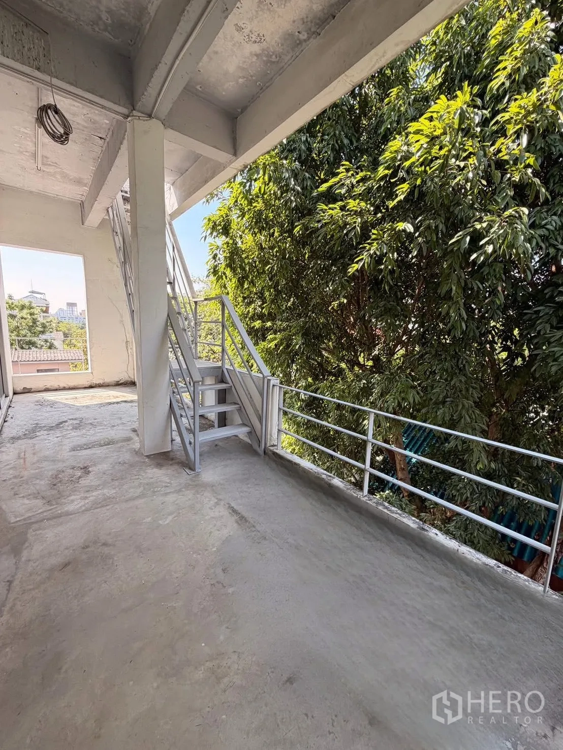 带办公室的家 for rent in Huai Khwang, Bangkok - 带金属楼梯和护栏的混凝土露台，旁有茂密树木。