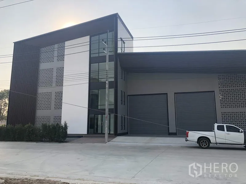 工厂 出售在Pathum Thani - 坦亚武里现代工厂外观，三层玻璃办公楼与双卷帘装卸门。