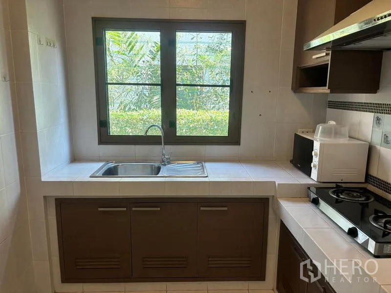 独立式住宅 出租在Bang Phli, Samut Prakan - 厨房水槽位于窗下，窗外是绿篱