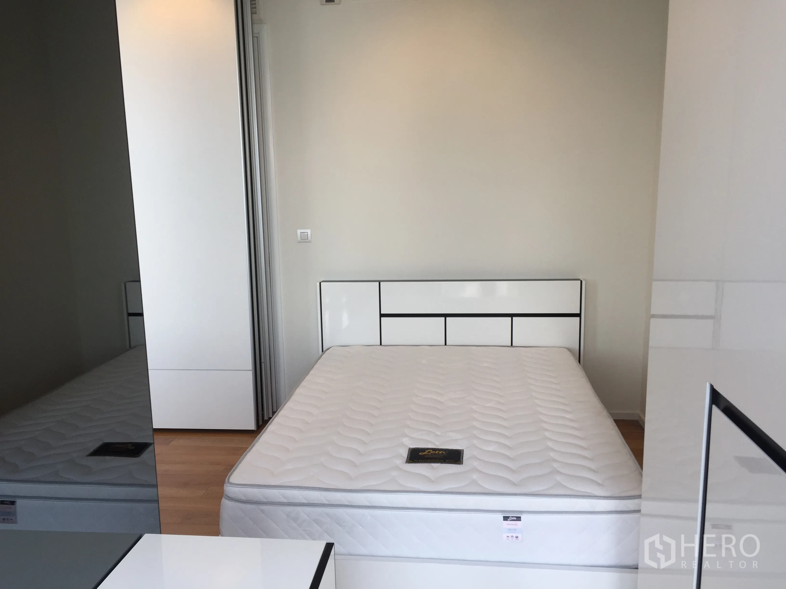 Condominium for rent in Ratchathewi, Bangkok - Second bedroom with minimalist bed, white headboard, and storage cabinets.
