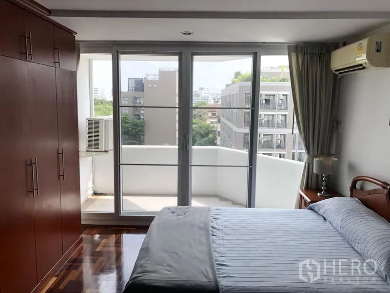 Condominium for rent or sale in Watthana, Bangkok - Second bedroom facing a private balcony with built-in wardrobe and city view.