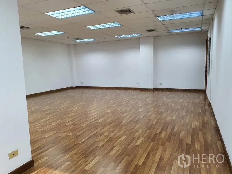 办公空间 出租在Watthana, Bangkok - 空置办公区，格栅吊顶、荧光灯与木纹地板。