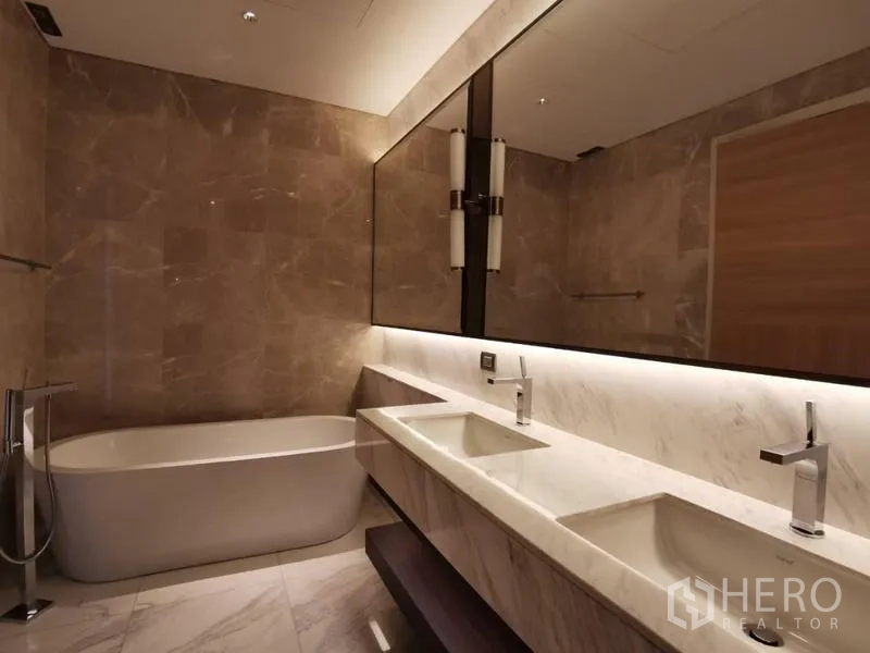 Condominium for rent in Pathum Wan, Bangkok - Master bathroom with soaking bathtub and double sinks in marble finish.