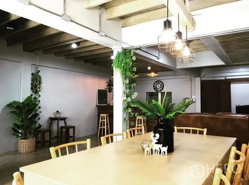 Townhouse for rent in Chatuchak, Bangkok - Open-plan dining area with long table, pendant lights and exposed beams.