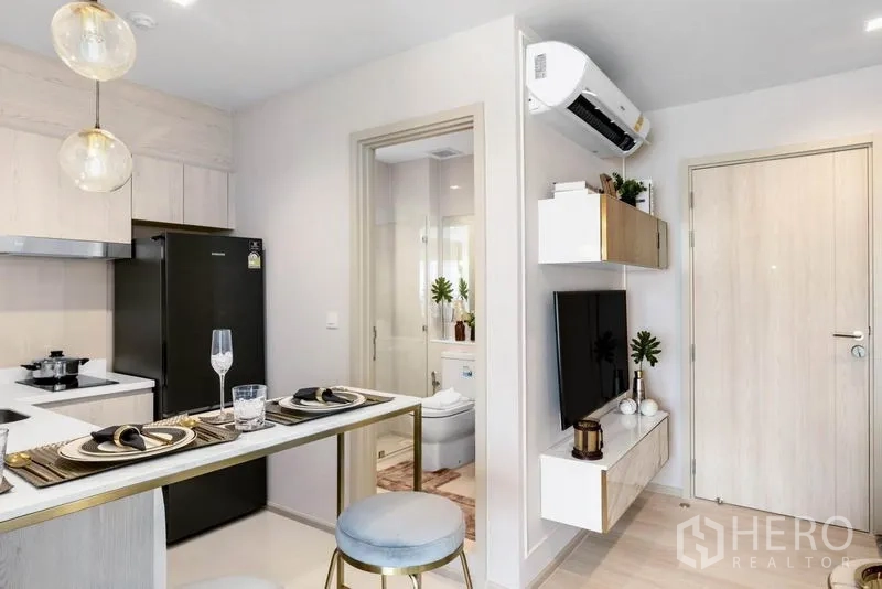 Condominium for sale in Pathum Wan, Bangkok - Compact kitchen with breakfast bar, built-in cabinetry and view to modern bathroom.