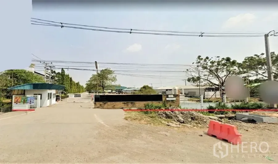 โรงงาน ขายในLam Luk Ka, Pathum Thani - ซุ้มประตูเข้าโครงการอุตสาหกรรมพร้อมป้อมยาม กำแพงรั้ว และถนนทางเข้าโล่งกว้าง