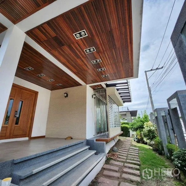 独立式住宅 出售在Phra Khanong, Bangkok - 前门门廊，木质吊顶、台阶与侧边小花园步道