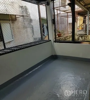 Shophouse for rent in Watthana, Bangkok - Covered rear balcony with mesh screens and painted concrete floor.