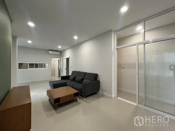Detached House for rent in Saphan Sung, Bangkok - Living room with sliding glass partition, recessed lights and air conditioning.