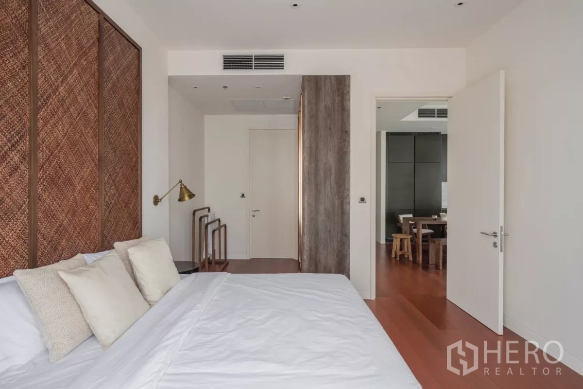 公寓 出租在Watthana, Bangkok - 安静卧室，白色床品、黄铜壁灯与木地板。