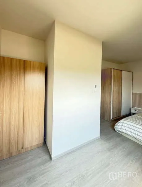 Townhouse for rent in Bang Phli, Samut Prakan - Bedroom corner showing two wardrobes and a partition wall with light wood flooring.