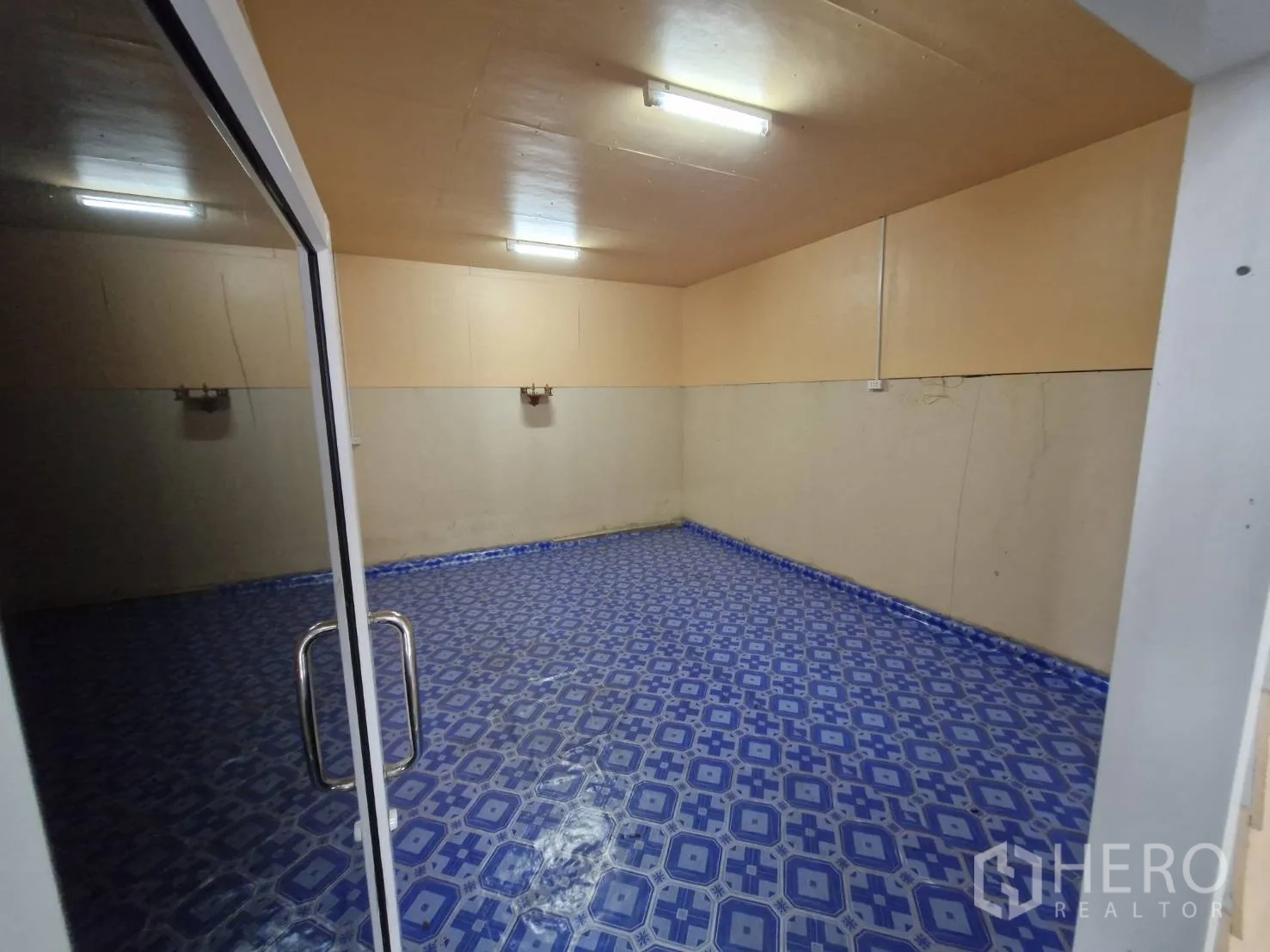 Warehouse for rent in Nakhon Pathom - Office room with fluorescent lighting and blue patterned tile flooring.