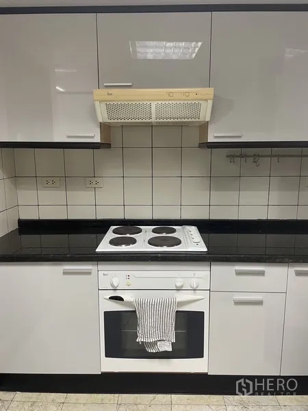 公寓 出租或出售在Pathum Wan, Bangkok - 厨房烹饪区，电炉灶、烤箱、瓷砖挡板与抽油烟机。