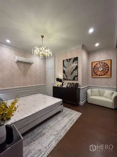 Detached House for sale in Bang Kapi, Bangkok - Elegant bedroom with chandelier, wainscoting and dresser on dark wood floor.