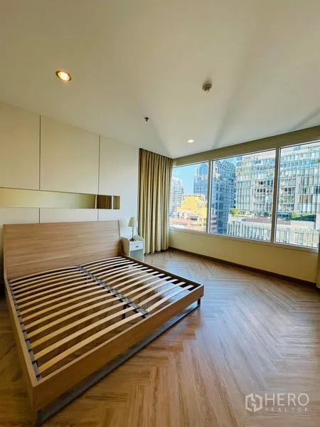 Condominium for rent in Bang Rak, Bangkok - Corner master bedroom with wide city-view window and wood flooring.
