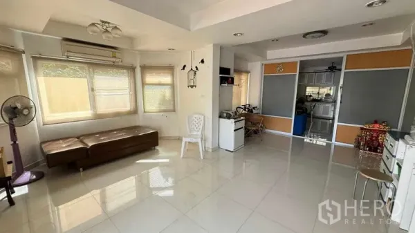 独立式住宅 出售在Mueang Pathum Thani, Pathum Thani - 采光充足的客厅，大窗户与亮面地砖，动线通往厨房。