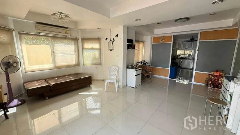 独立式住宅 出售在Mueang Pathum Thani, Pathum Thani - 采光充足的客厅，大窗户与亮面地砖，动线通往厨房。
