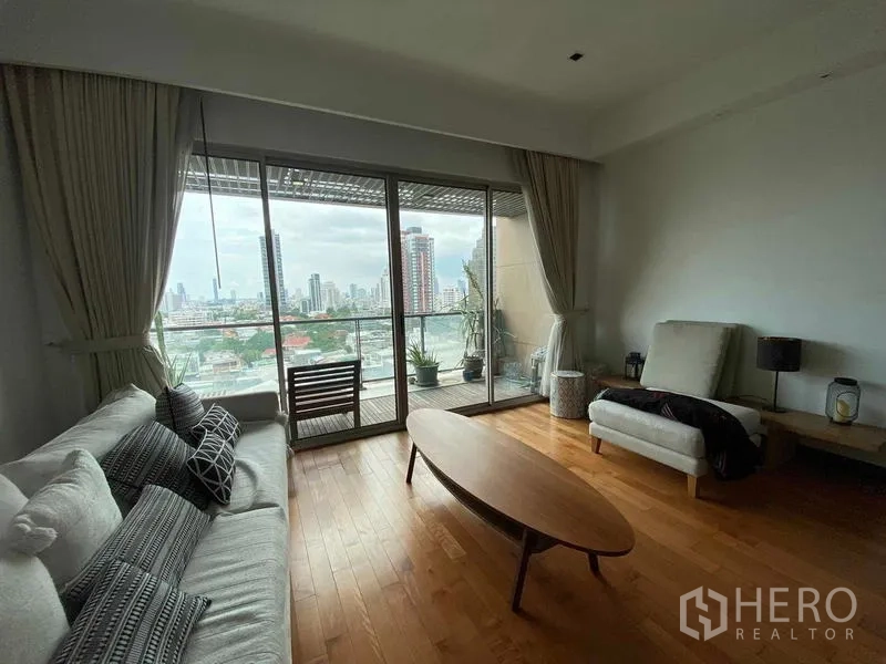 公寓 出租在Yan Nawa, Bangkok - 明亮客廳，木地板與沙發組，推拉玻璃門通向可觀景的陽台。