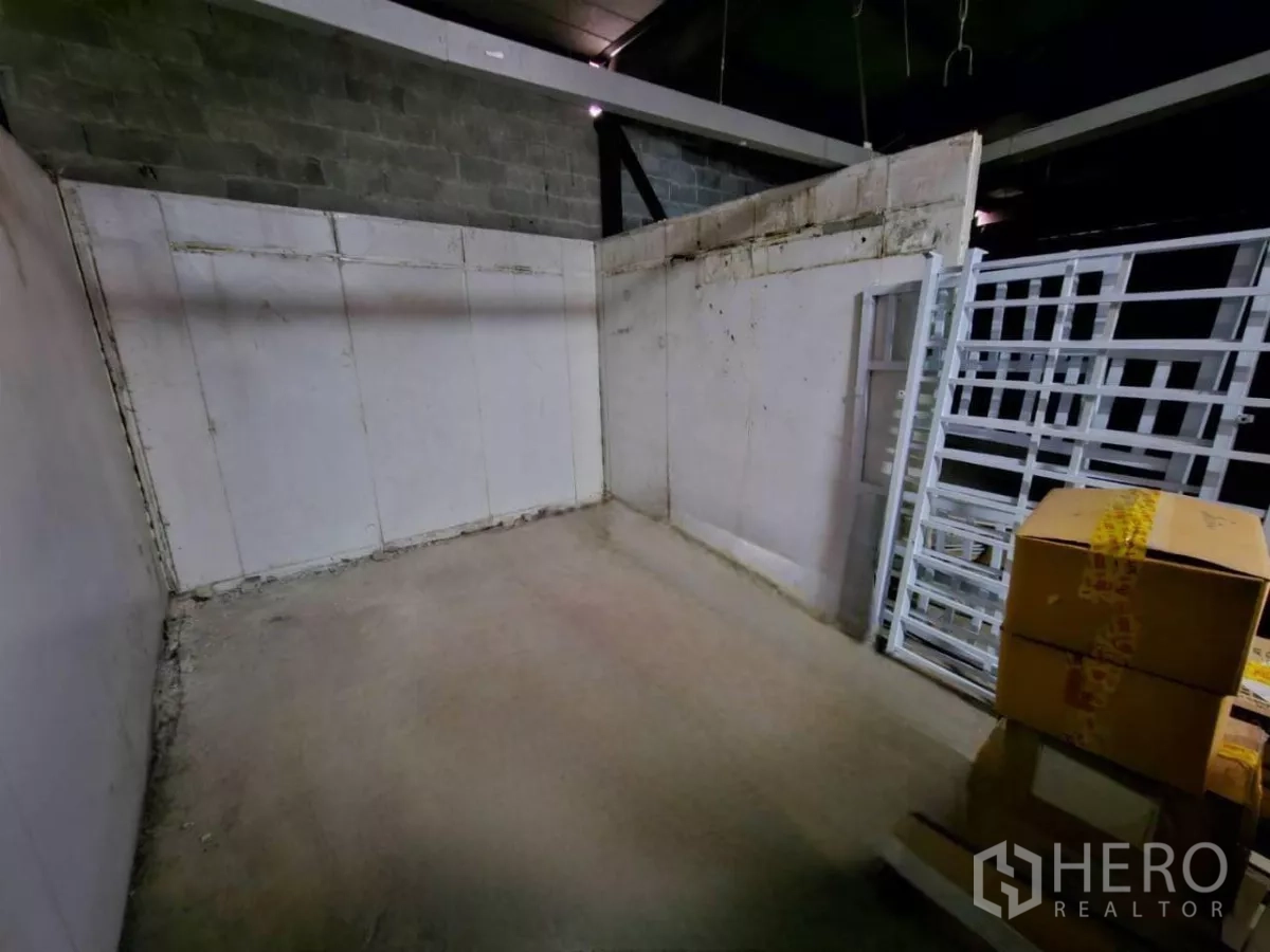 Warehouse for rent in Chatuchak, Bangkok - Small storage corner with boxes and stacked metal frames on concrete floor.